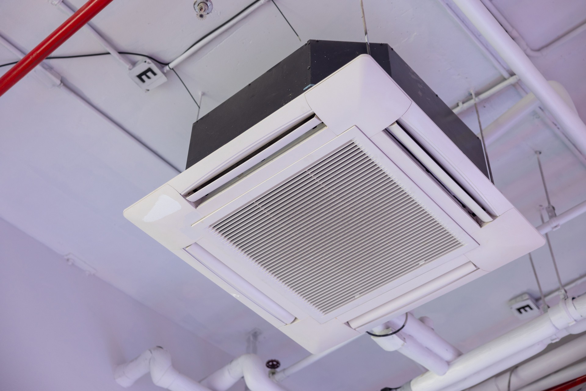 A white air conditioner is hanging from the ceiling. cassette type air conditioner.